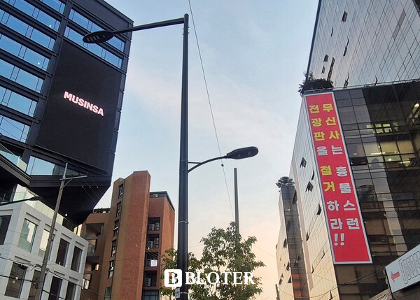 5일 오후 서울 성수동. 좁은 도로를 사이에 두고 무신사의 초대형 LED 전광판과 이를 겨냥한 붉은 플래카드가 맞서 있다. /사진=이유리 기자 